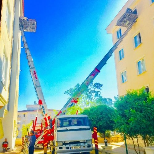 Sarı binada cephe asansörüyle yüksek kat taşıması