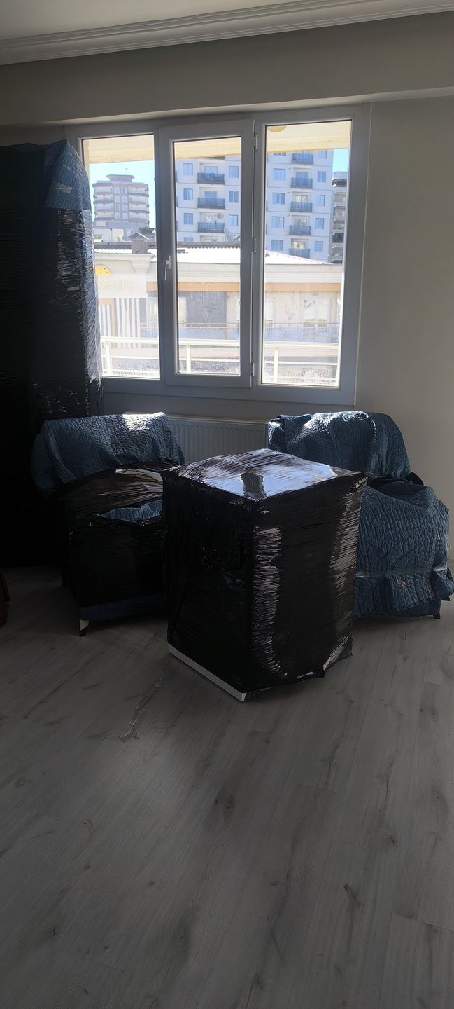 Odasında koruma örtüsüyle paketlenmiş gardırop ve mobilyalar