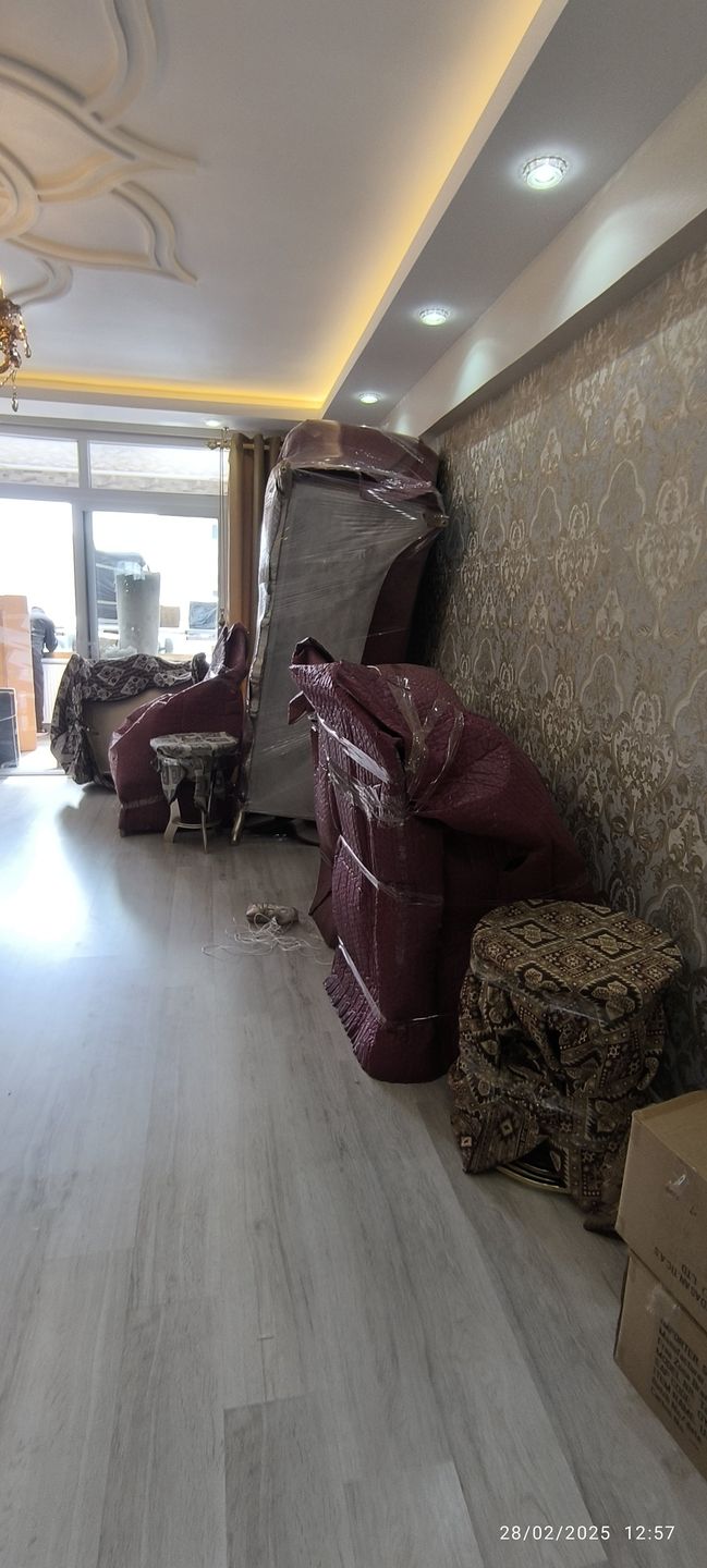 Salonda duvar dibine dizilmiş paketlenmiş mobilyalar